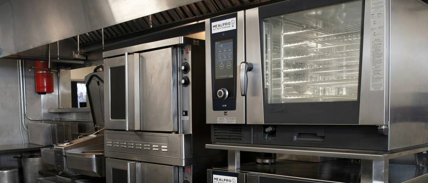A modern commercial kitchen in Ontario, with staff using digital checklists and temperature logs for food safety compliance