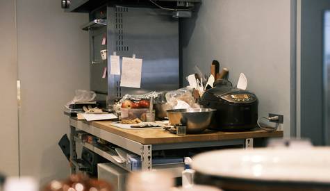 A clean commercial kitchen workspace with food safety signage and staff in uniform