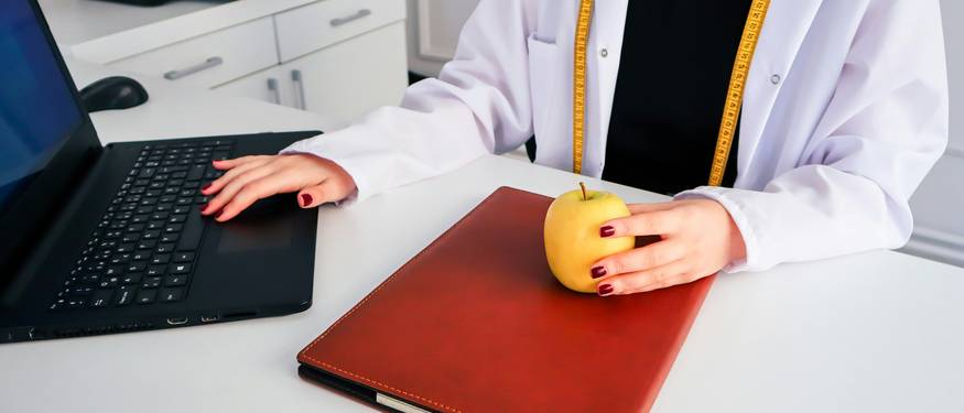 Ontario food handler completing online certification on a laptop beside a classroom-based food safety exam